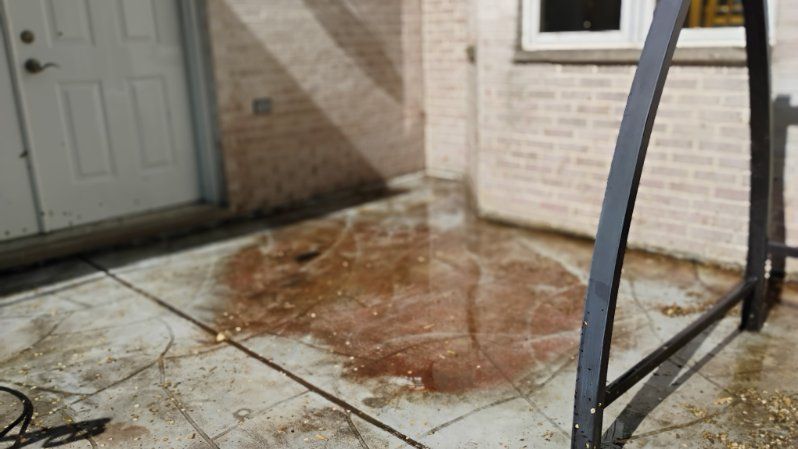 A dirty concrete patio in front of a brick house.