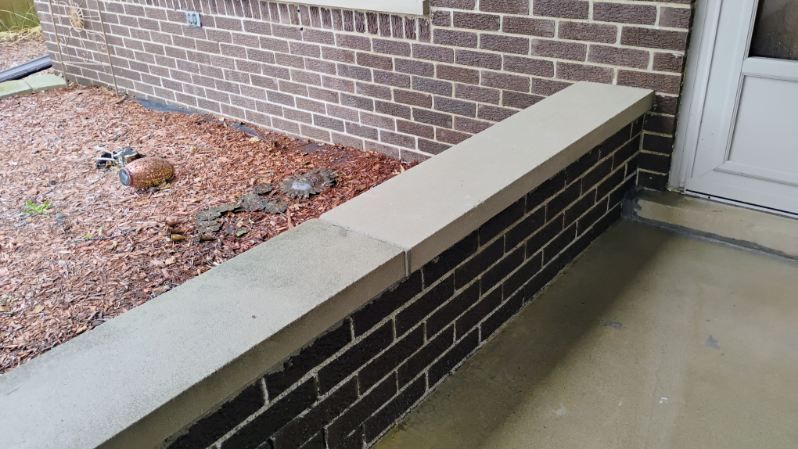 A brick wall with a concrete ledge next to a door.