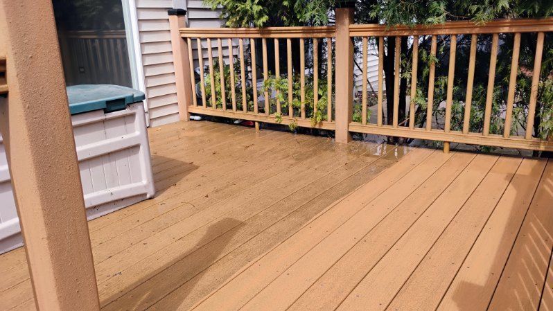 A wooden deck with a wooden railing and a sliding glass door.