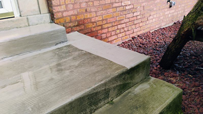 A set of concrete steps leading up to a brick wall.