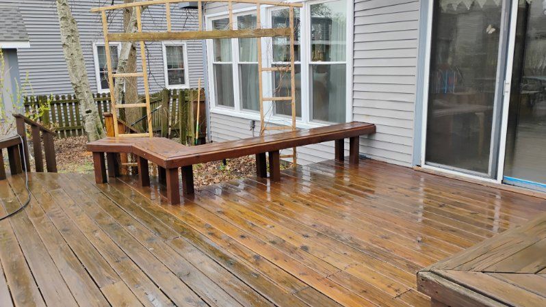 A wooden deck with a bench and stairs in front of a house.