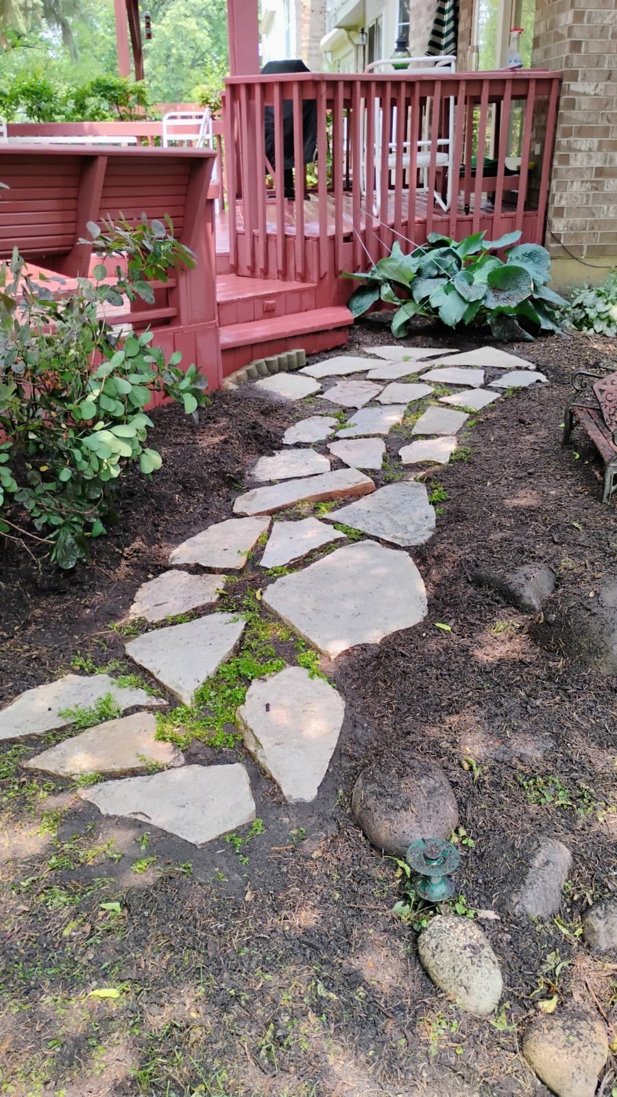 A stone walkway leading to a deck with a gazebo in the background.
