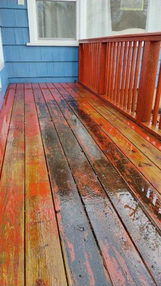 A wooden deck with a red railing and a blue house in the background.