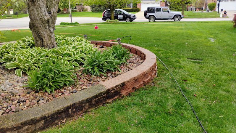A car is parked on the side of the road in front of a lush green lawn.