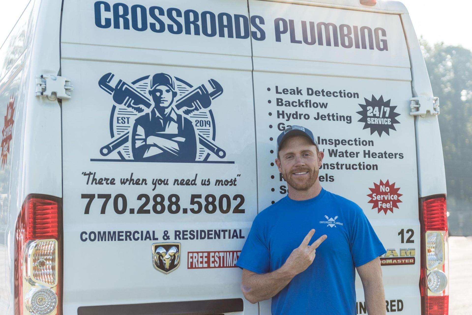 A man standing in front of a crossroads plumbing van