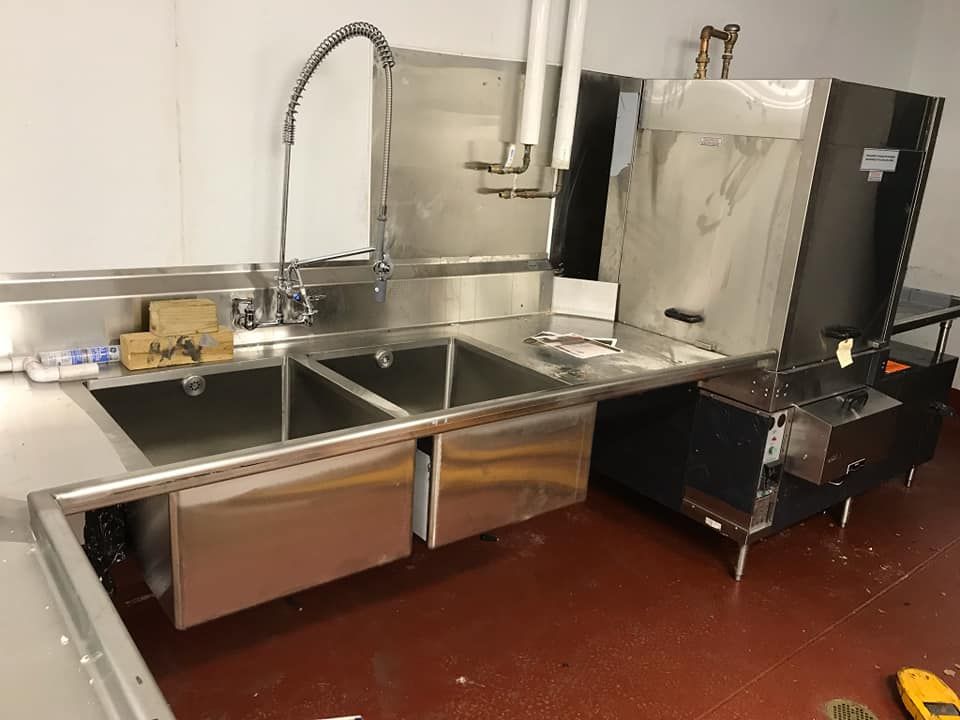 A kitchen with two stainless steel sinks and a dishwasher.