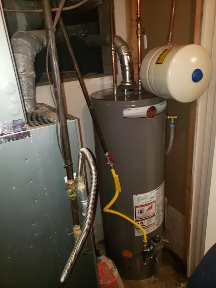A water heater is sitting in a room next to a furnace.