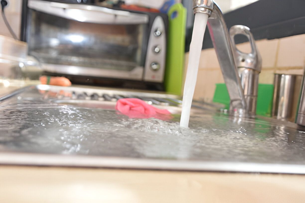 A close up of a kitchen sink with water running from the faucet.