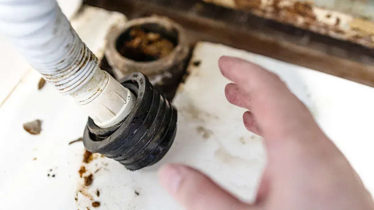 A person is fixing a drain pipe in a sink.