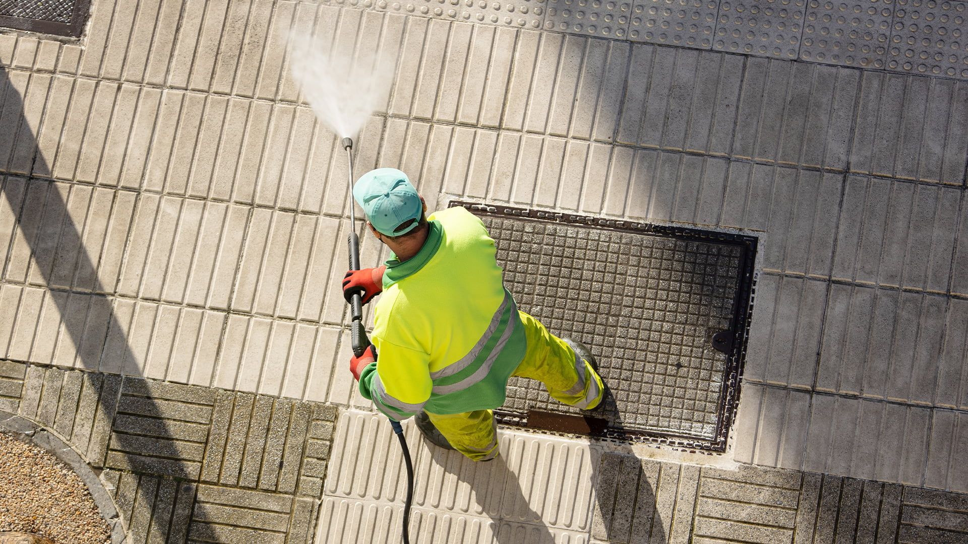 A man is cleaning the sidewalk with a high pressure washer.