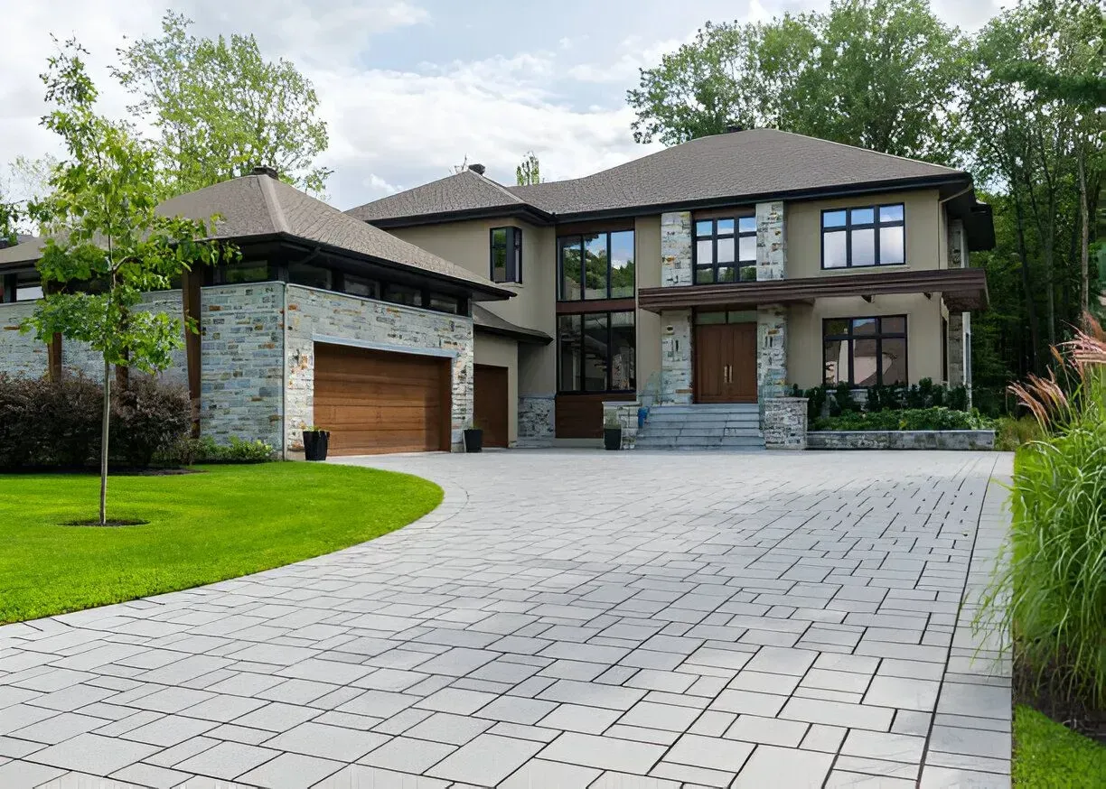 Modern house with gray paver driveway, light-colored exterior, and stone accents.