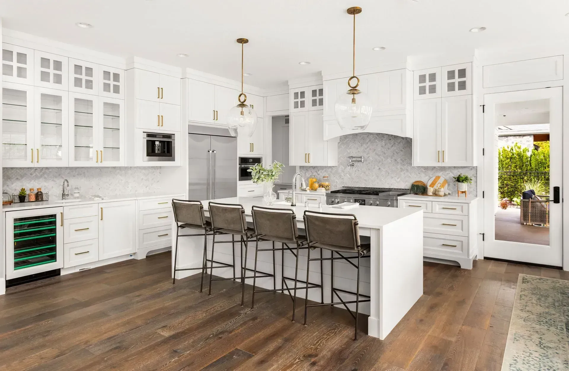 White modern kitchen with island, wood floor, and gold accents.