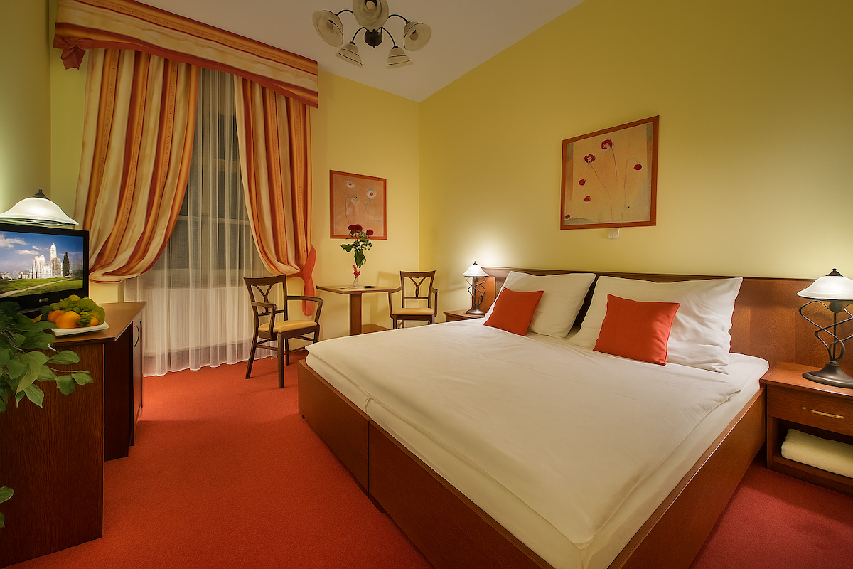 A hotel room with a bed , chairs , table and television.