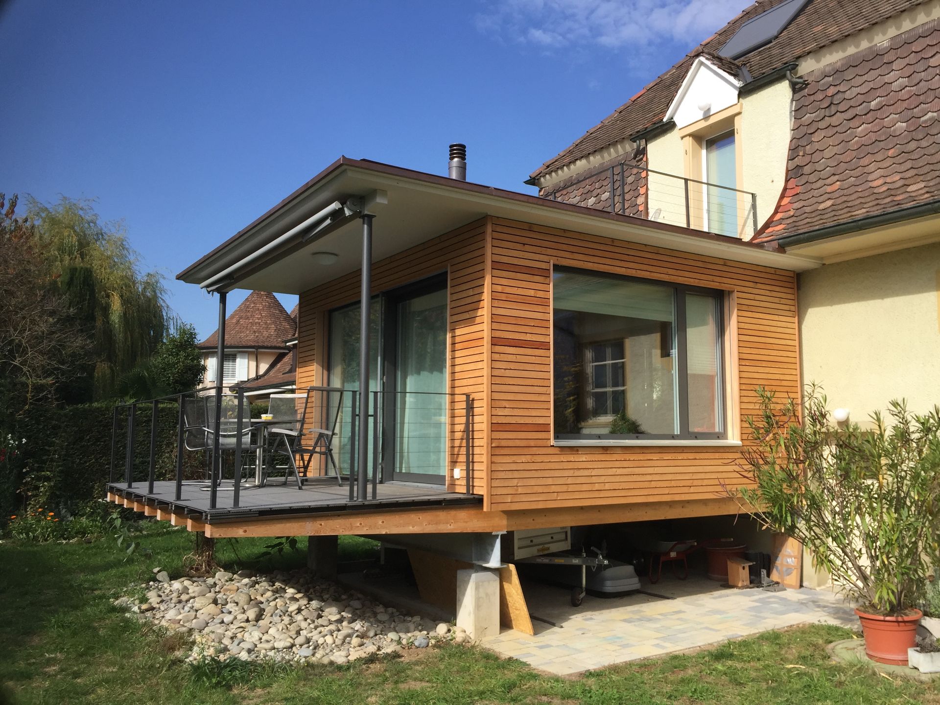 Mitten auf einem unbefestigten Feld wird ein Holzhaus gebaut.