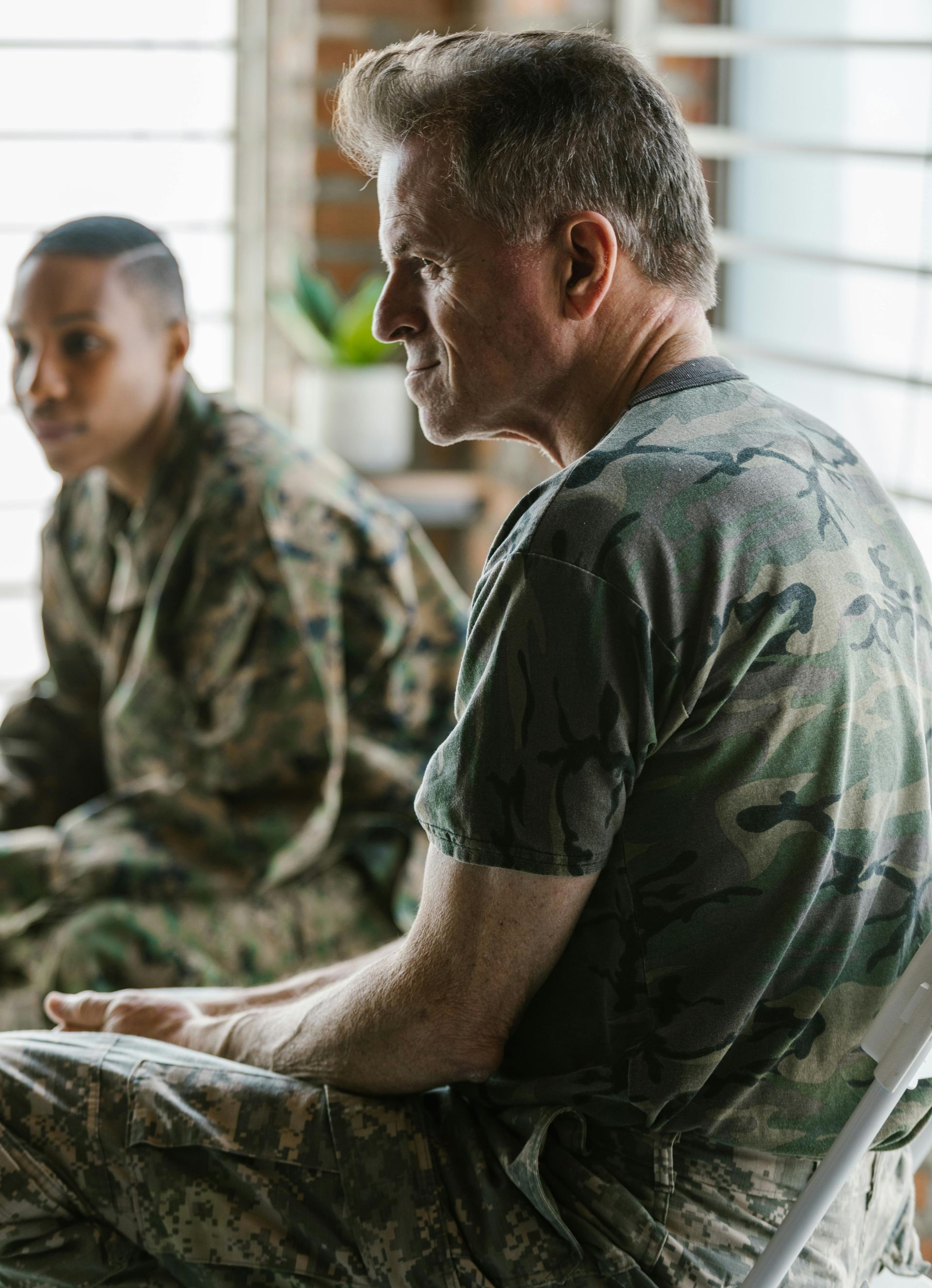 A man in a military uniform is sitting in a chair next to a woman in a military uniform