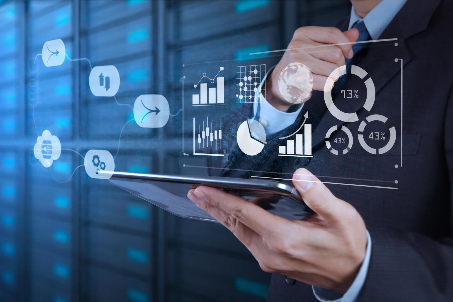 Homem de terno segurando um tablet que exibe visualizações de dados em uma sala de servidores.
