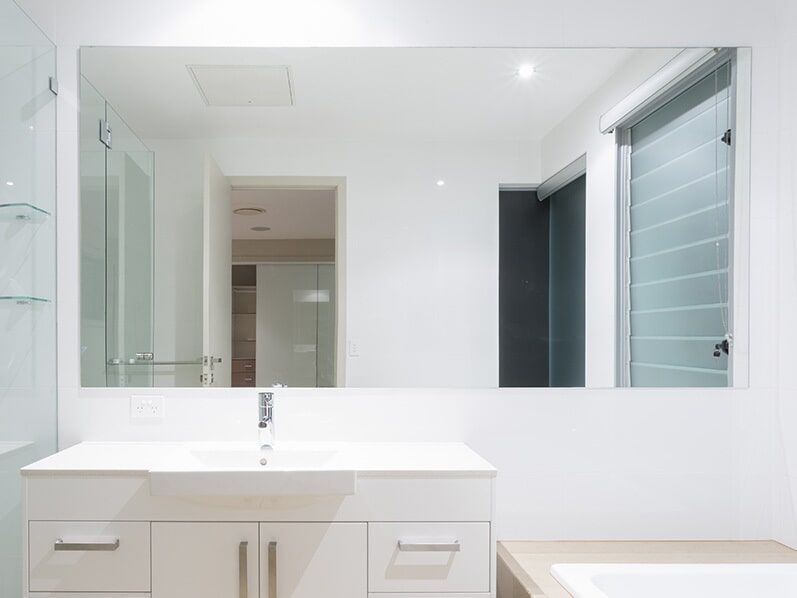 A custom cut mirror installed over a sink in a bathroom in Cairns