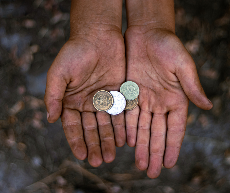 Hands, palms up, holding a few coins. Dirty, textured background.