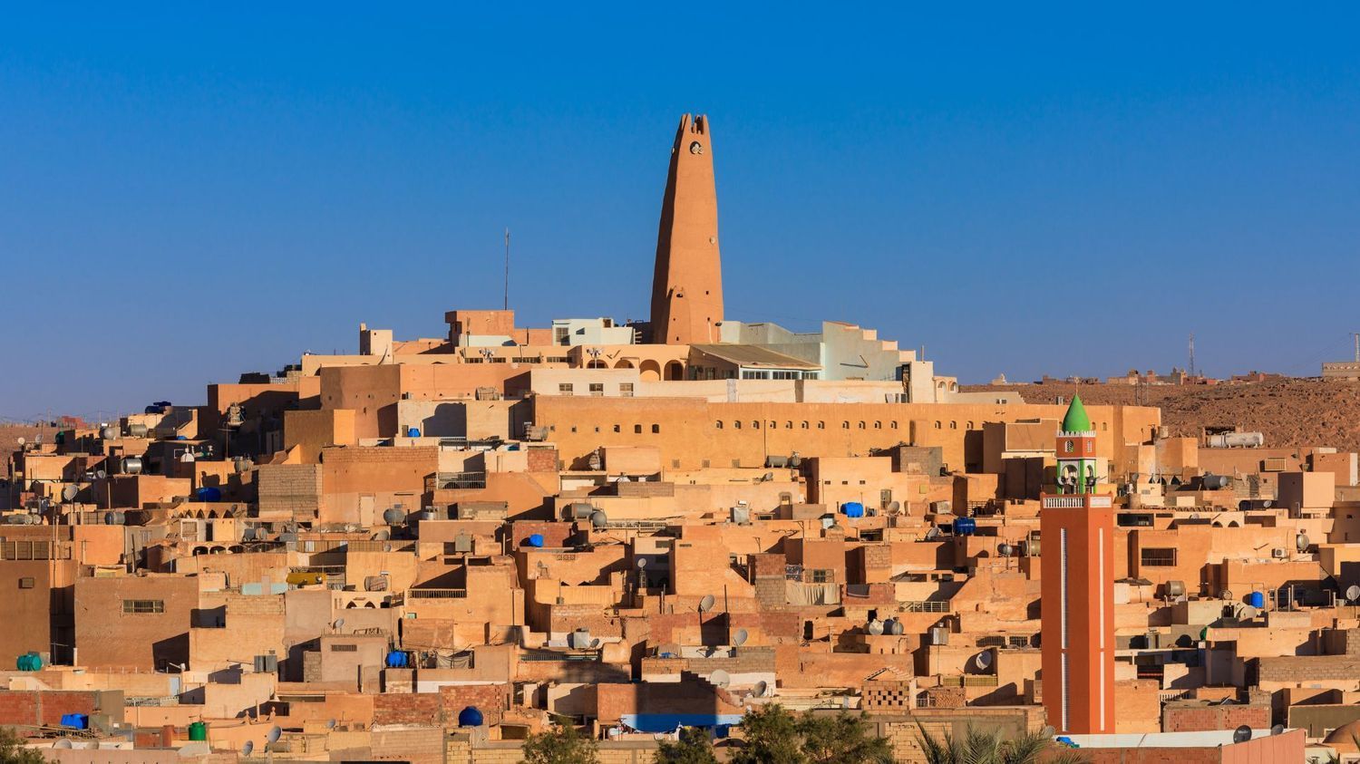 Ghardaia, Algeria: A historic town featuring earth-toned buildings with a central minaret under a clear blue sky.