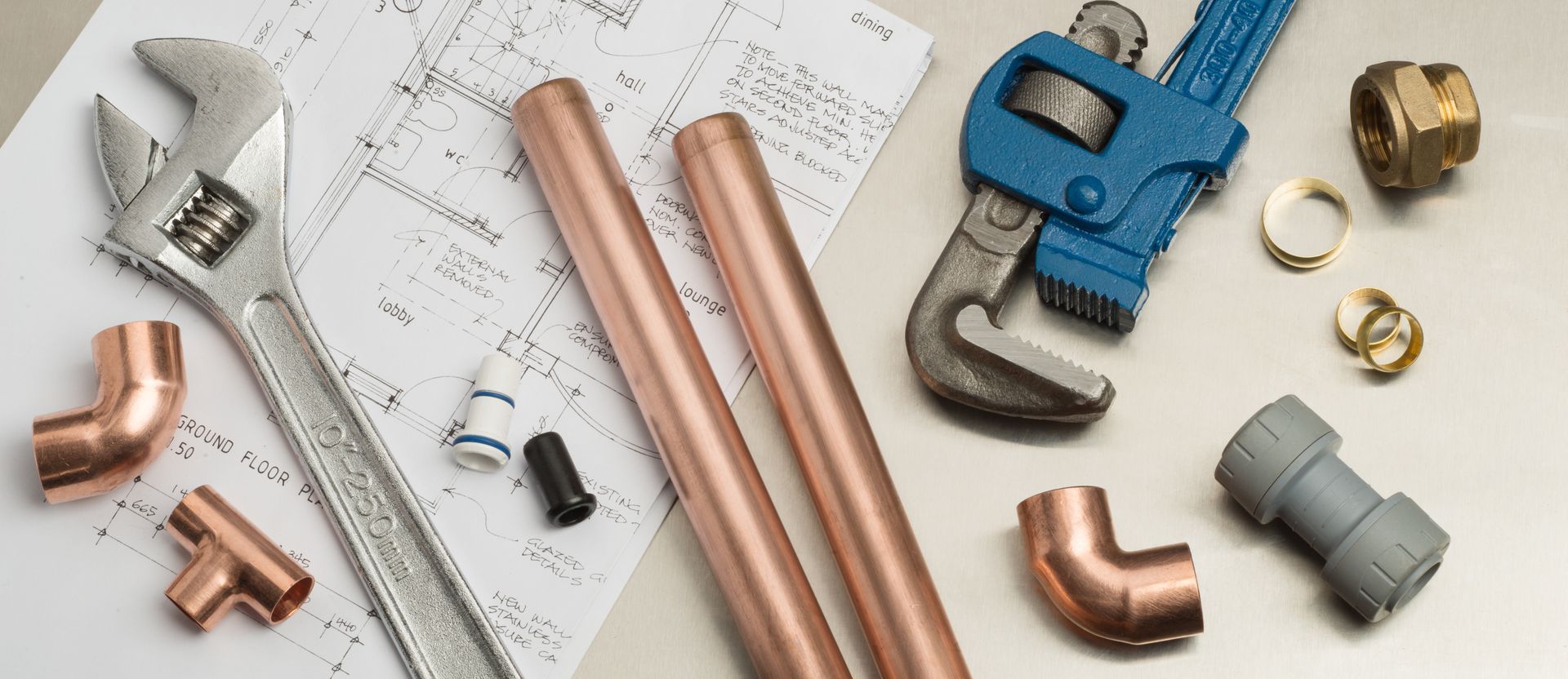 Plumbing materials and tools highlighting expert plumbing services displayed over house plans.