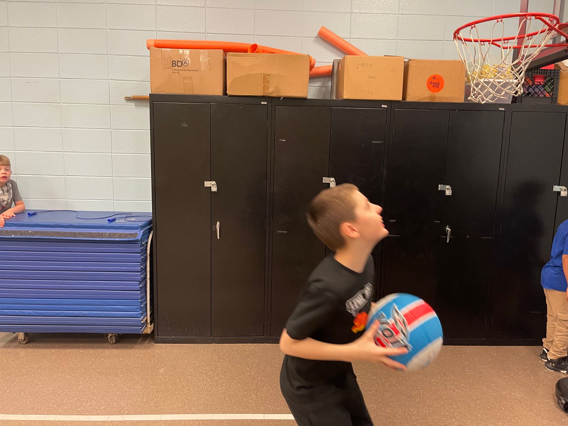 a young boy is holding a basketball in a gym .