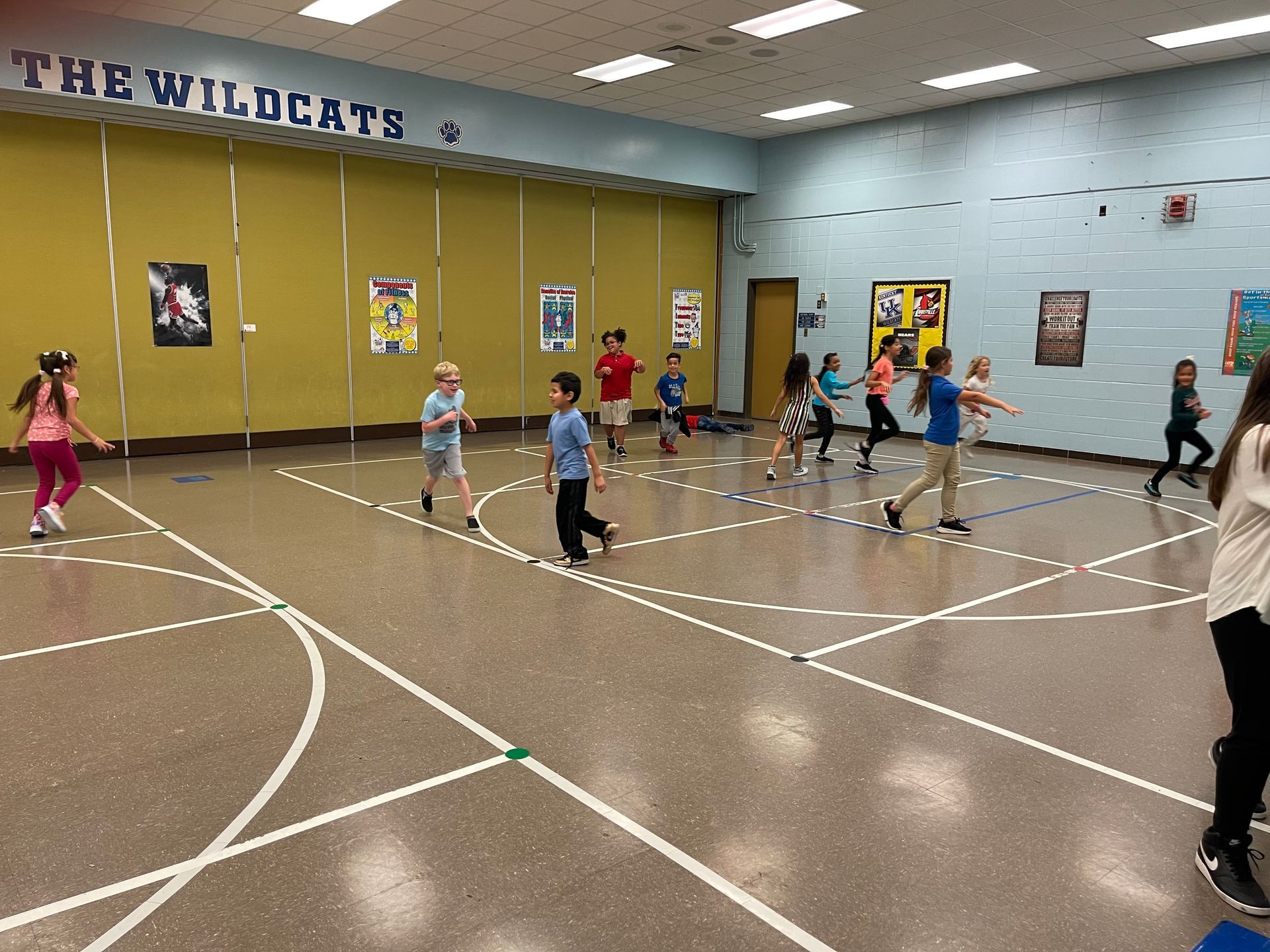 a group of children are playing basketball in a gym .