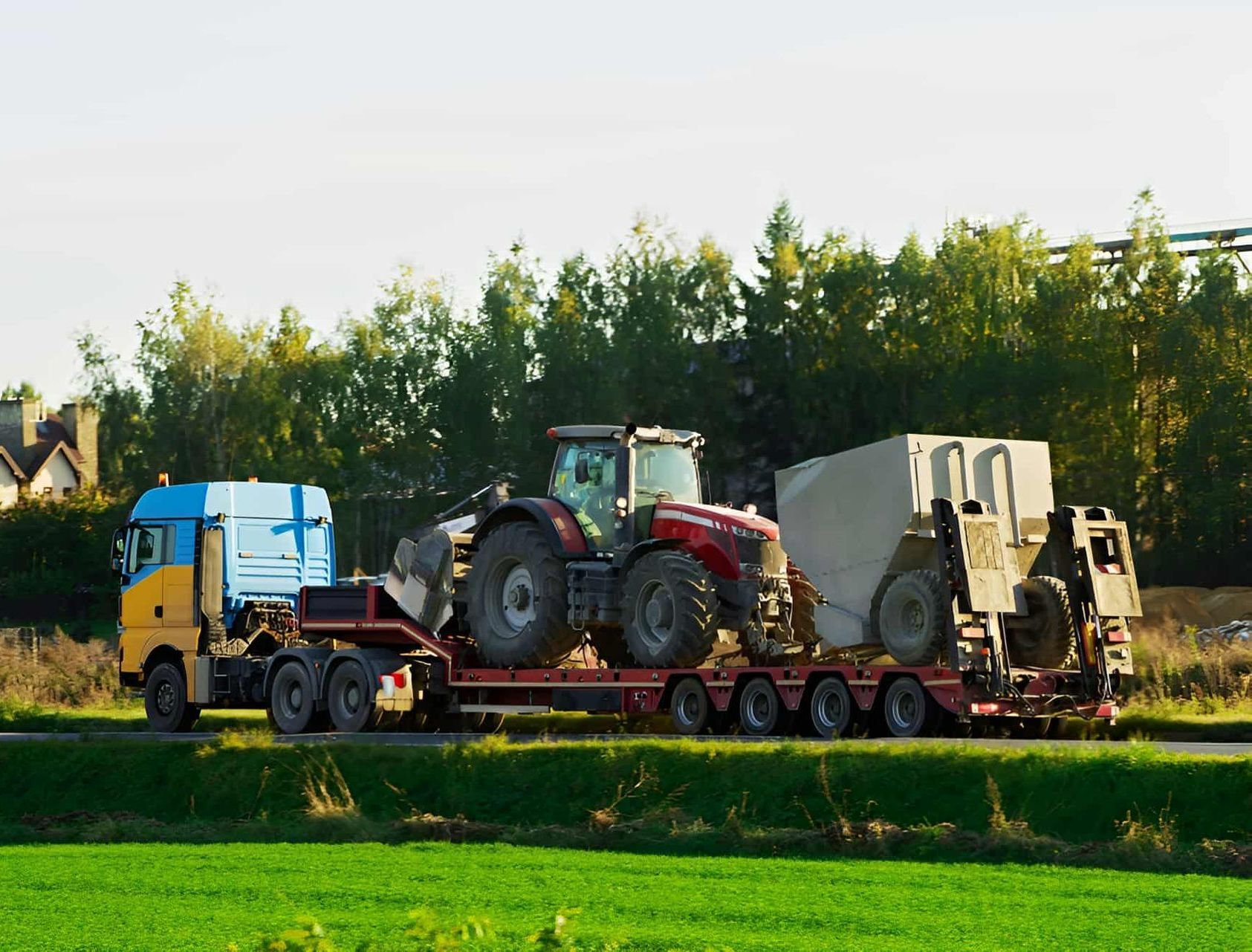 A Semi Truck Is Carrying A Tractor On A Trailer — Central Desert Transport In Ciccone, NT
