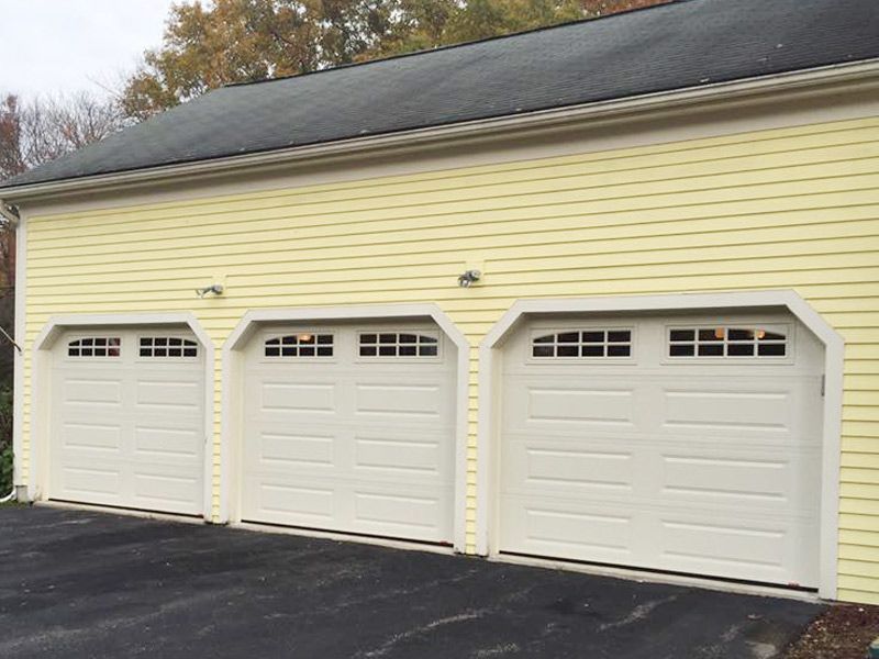 There are three garage doors on the side of a house.