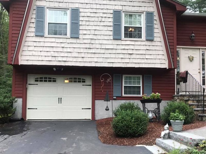 A red house with a white garage door and blue shutters