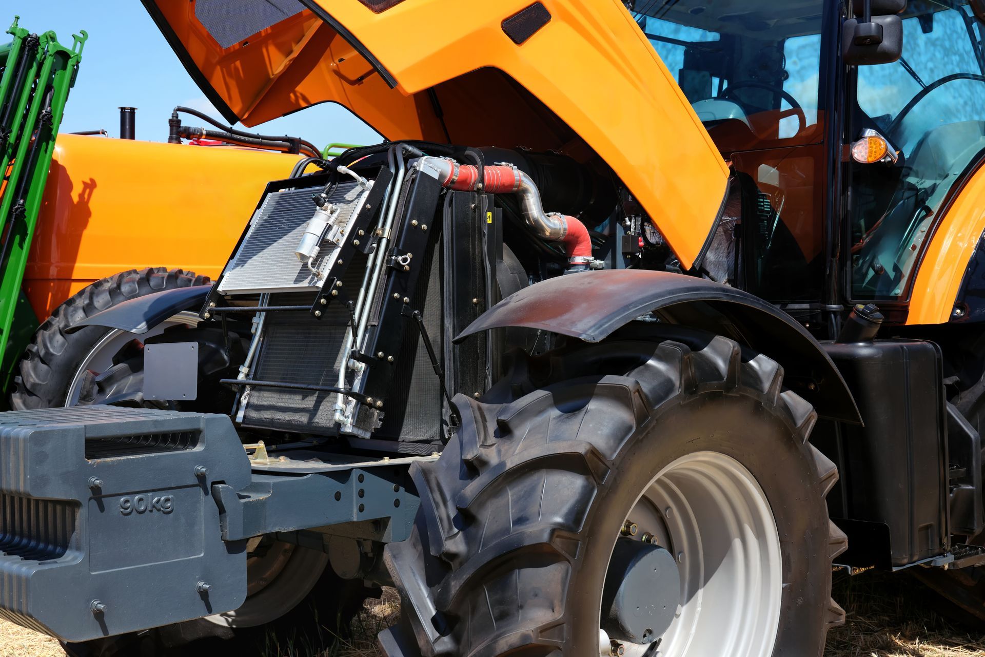 Orange and black tractor with the hood open, displaying engine components.