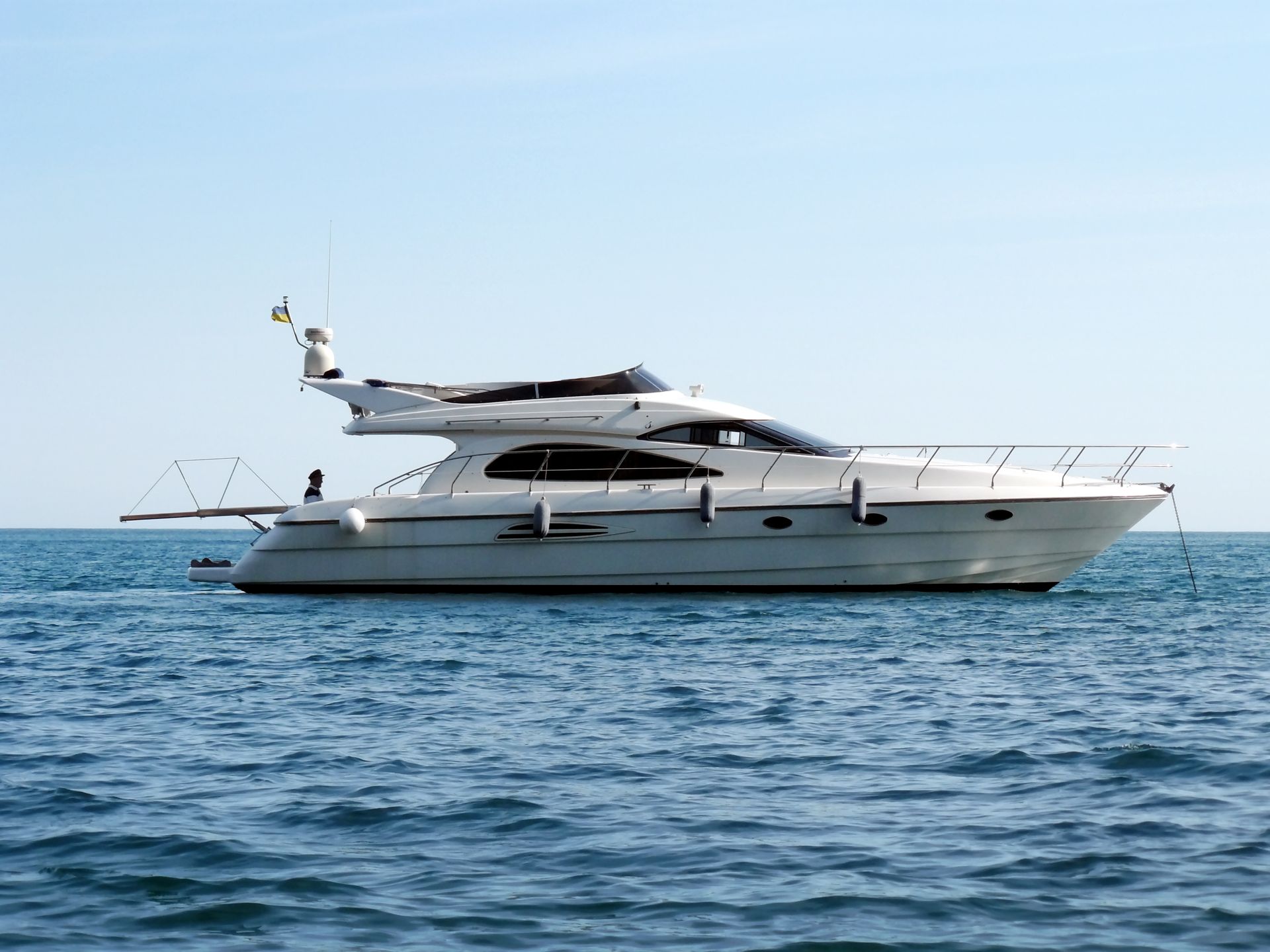 White yacht floating on blue water under a clear sky.