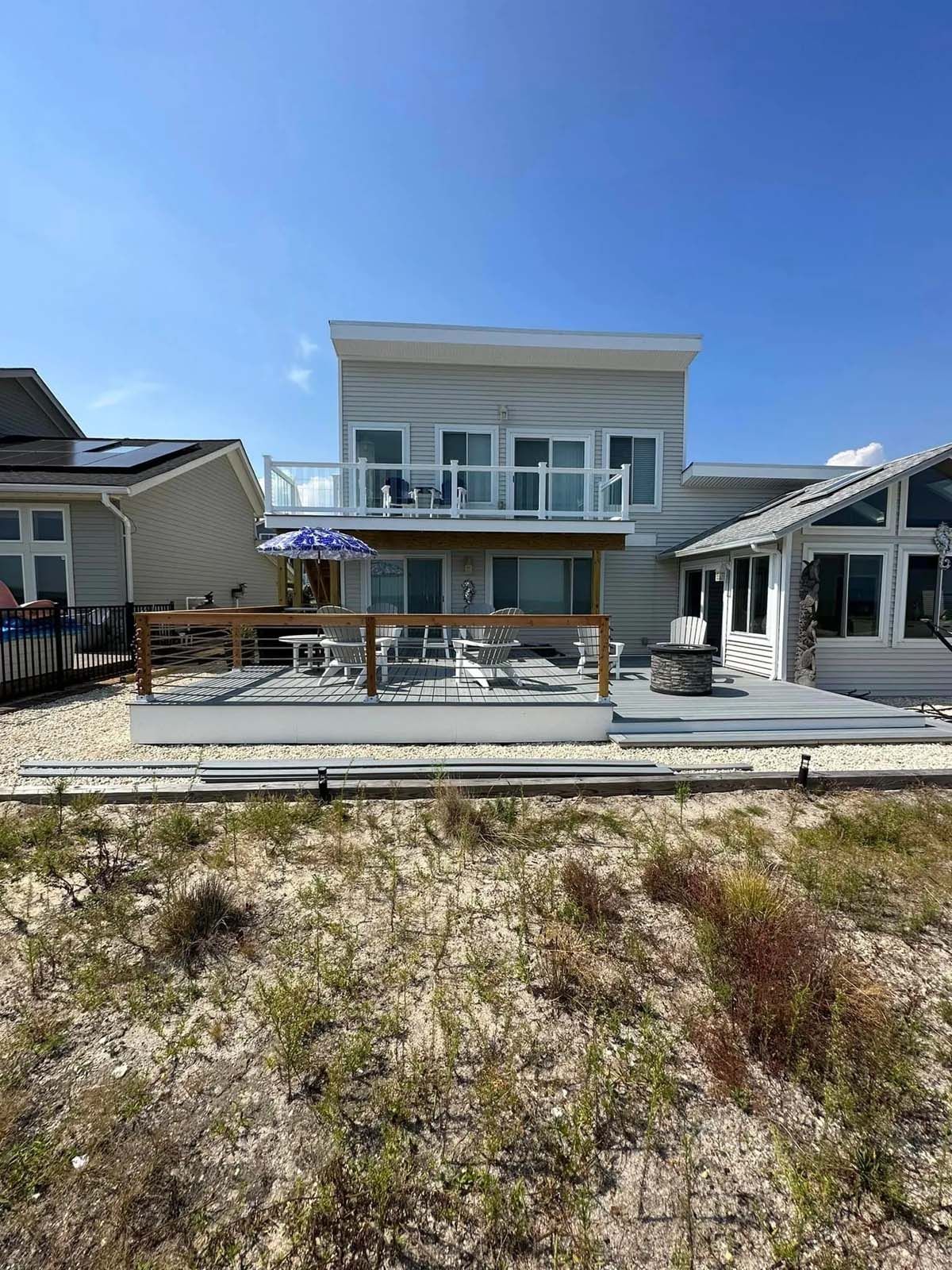 A large white house with a large deck on the beach.