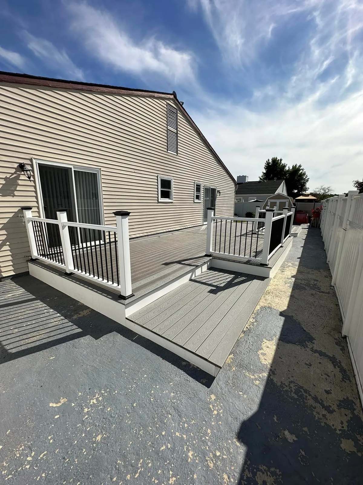 A large deck with a white railing is in front of a house.