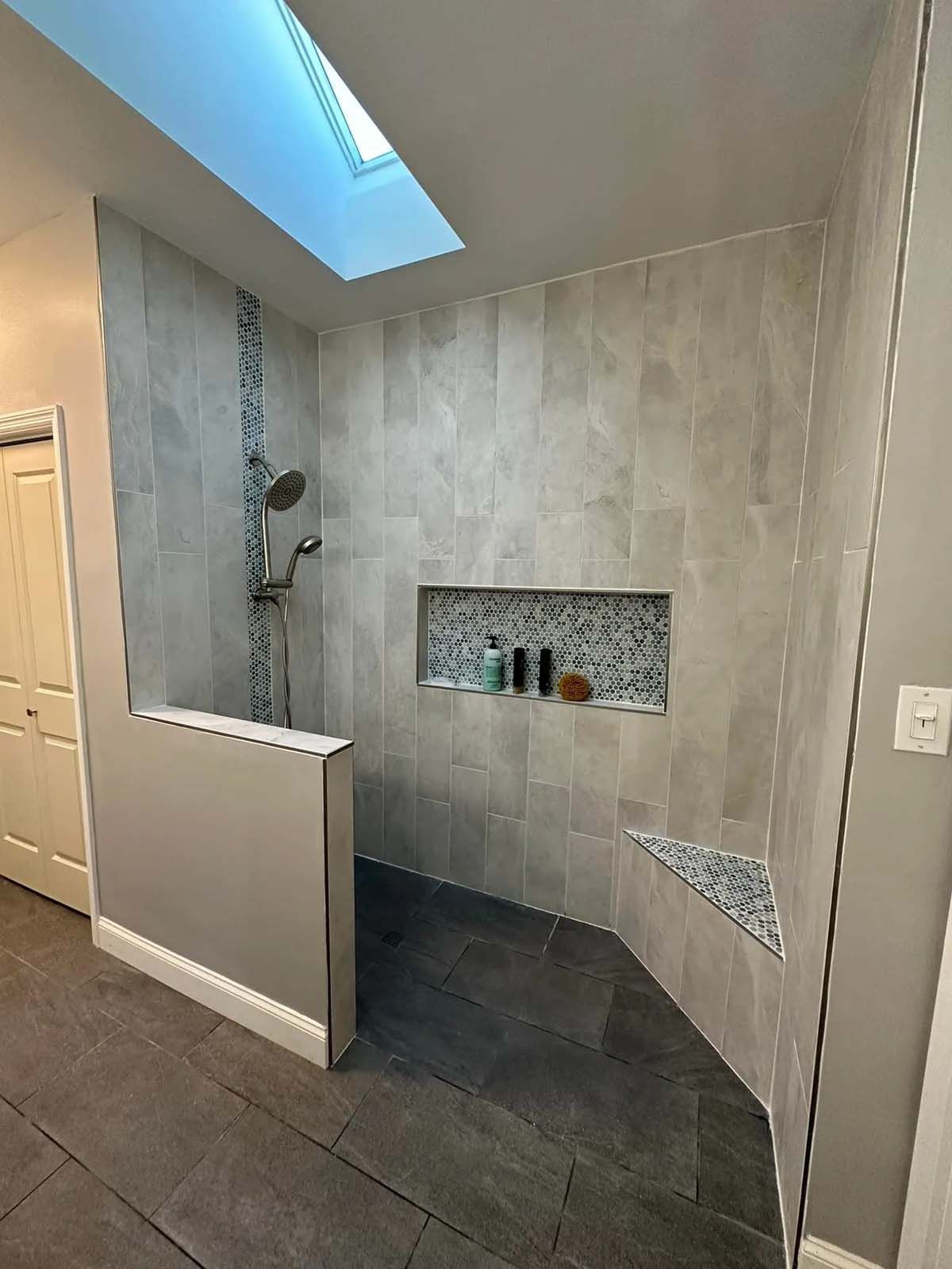 A bathroom with a walk in shower and a skylight.