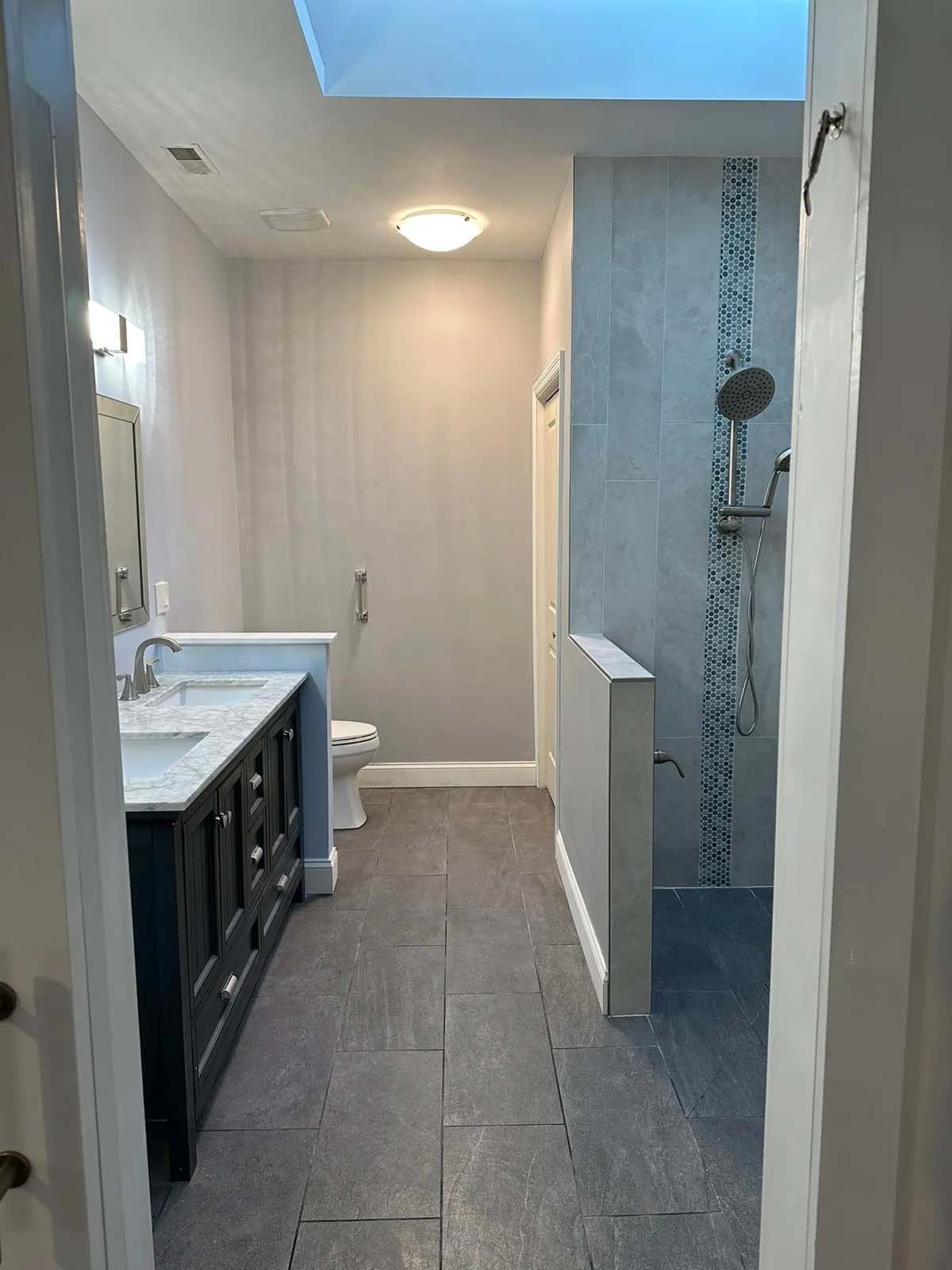 A bathroom with a sink , toilet , shower and skylight.