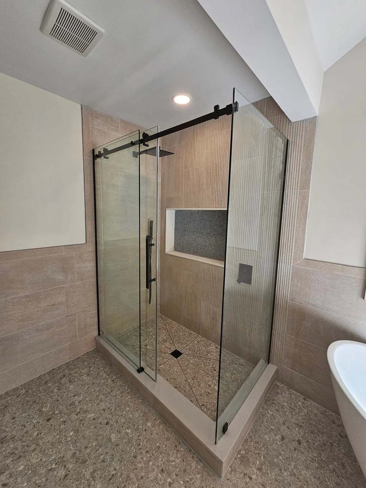 A bathroom with a sliding glass shower door and a bathtub.