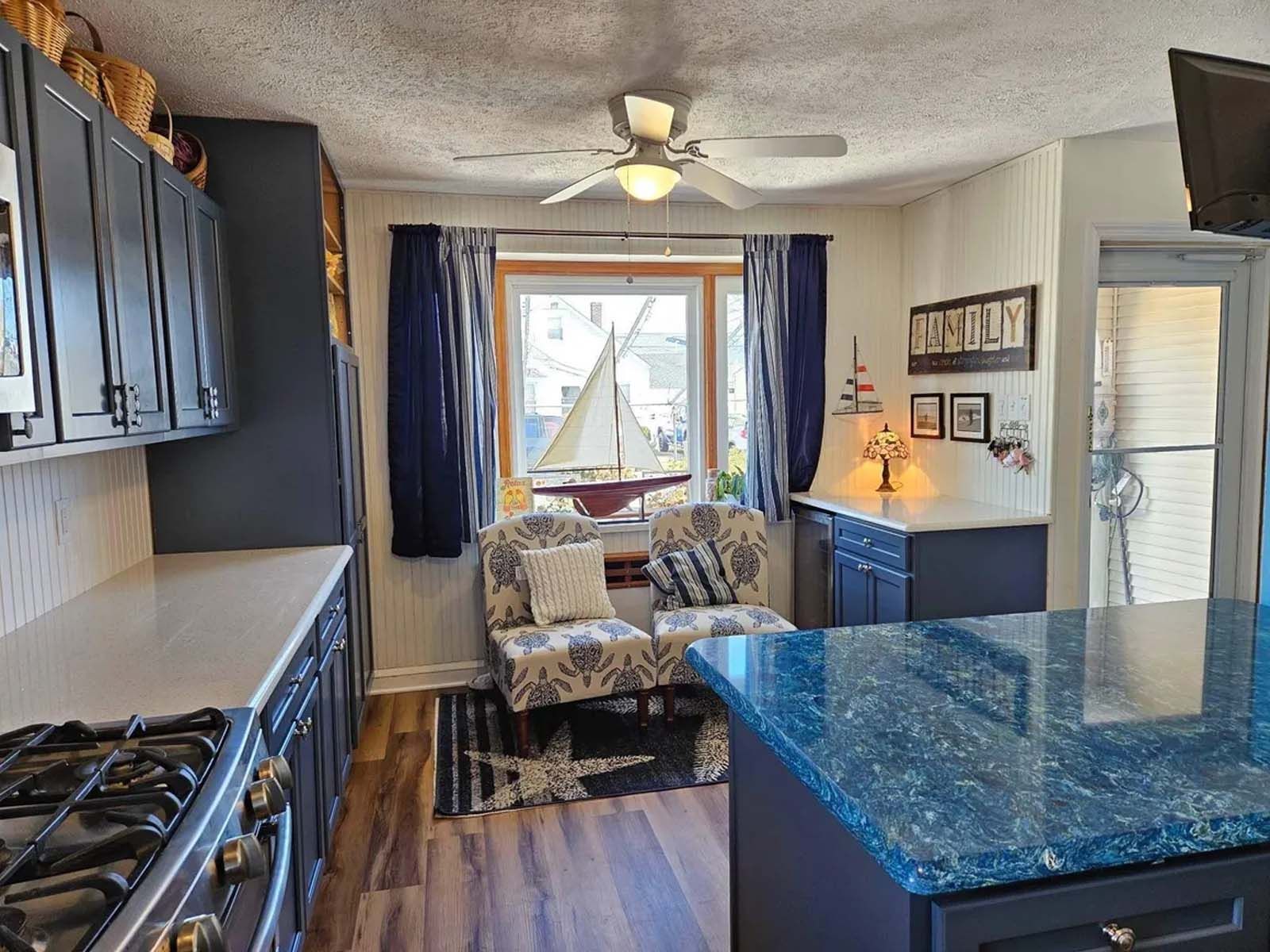 A kitchen with a stove , sink , and a ceiling fan.