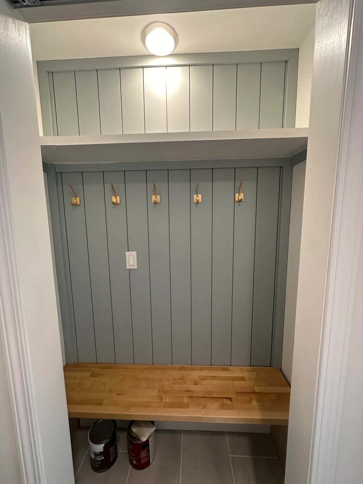 A closet with a wooden bench and hooks on the wall.