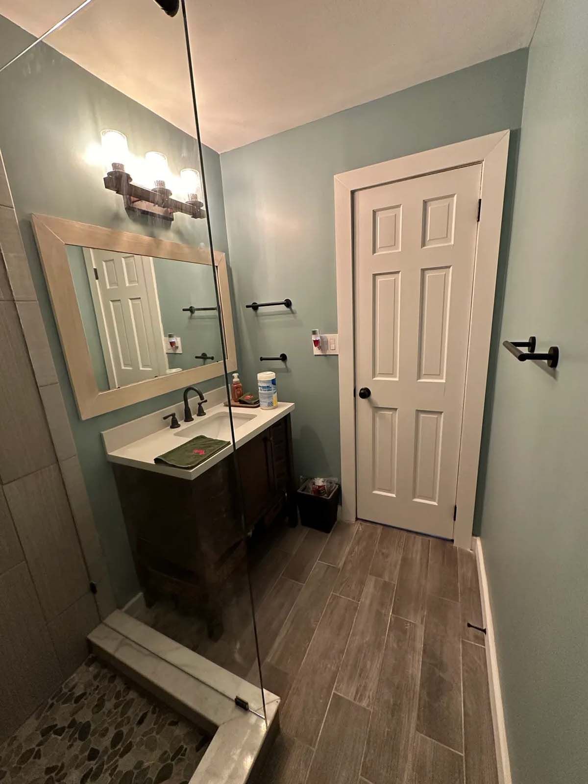 A bathroom with a sink , mirror , and walk in shower.