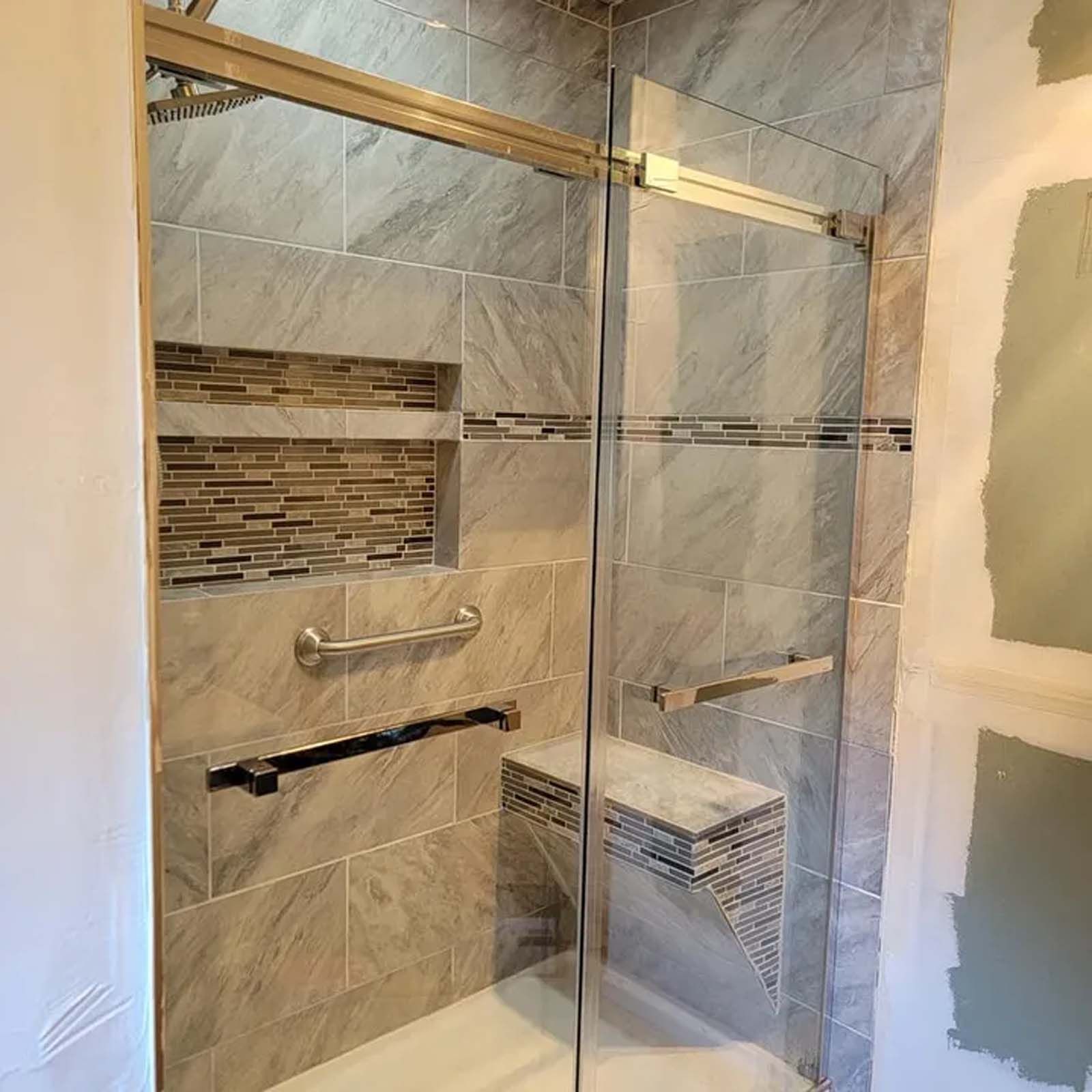 A bathroom with a sliding glass shower door and a bench.