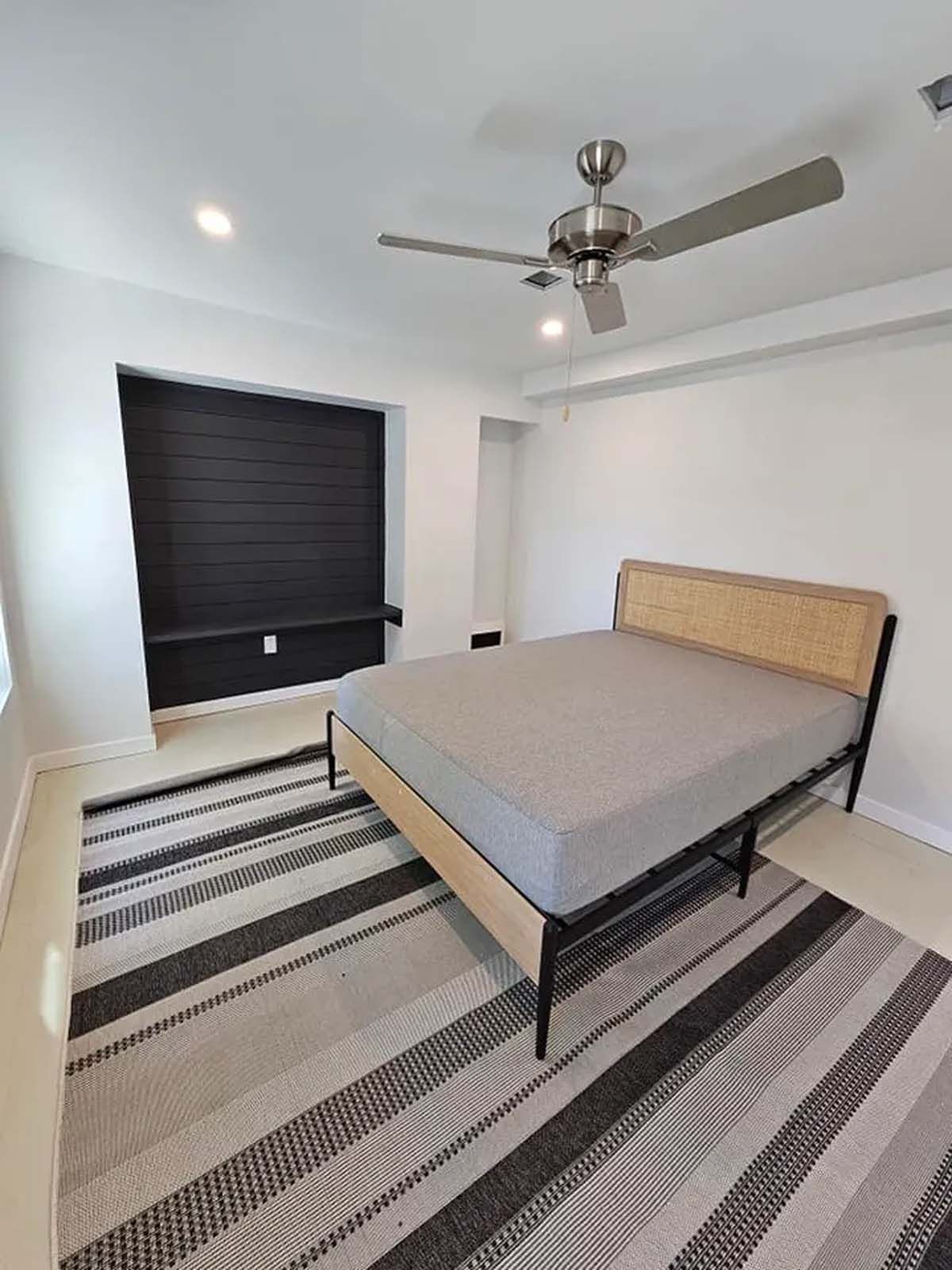 A bedroom with a bed , rug and ceiling fan.