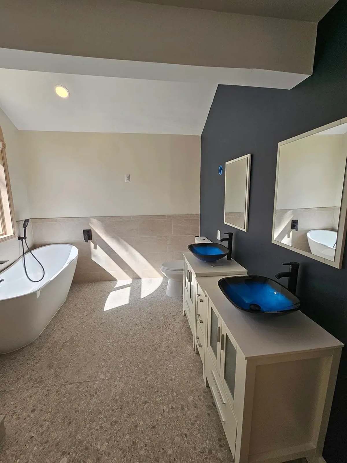A bathroom with two sinks , a bathtub and two mirrors.
