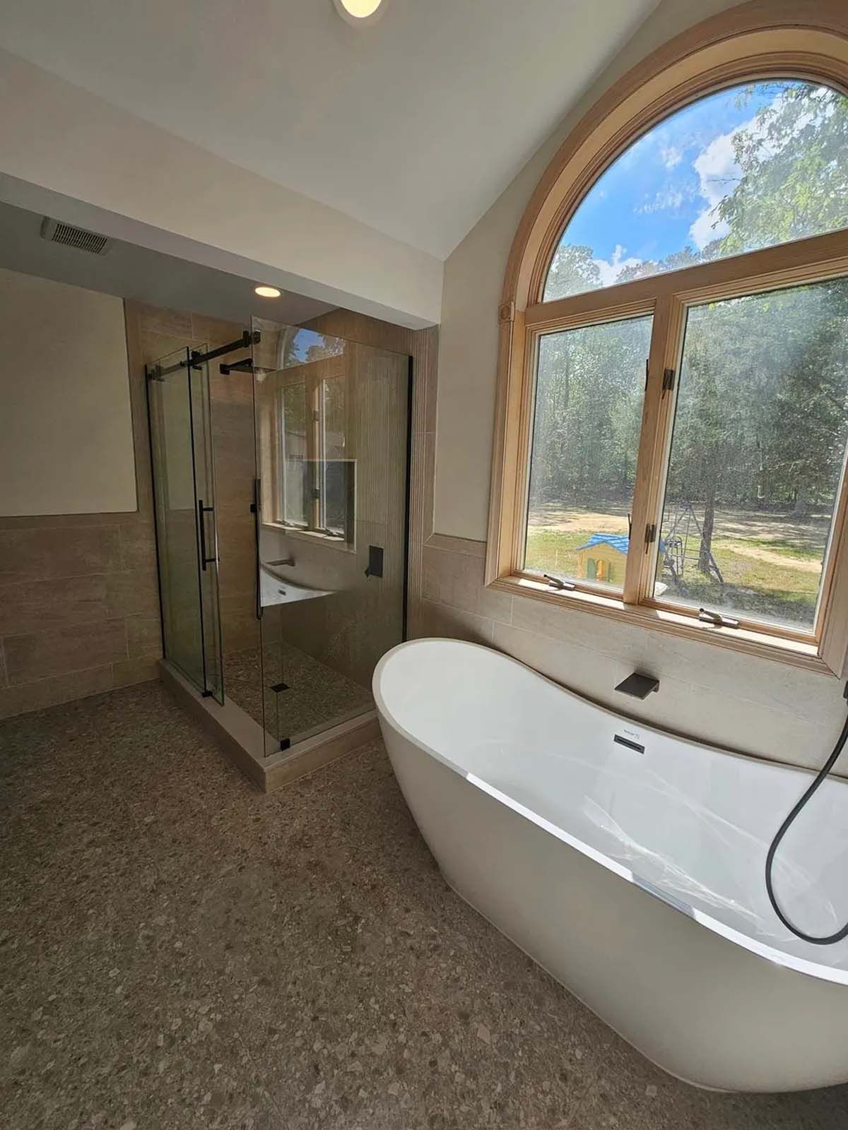A bathroom with a tub , shower , and large window.