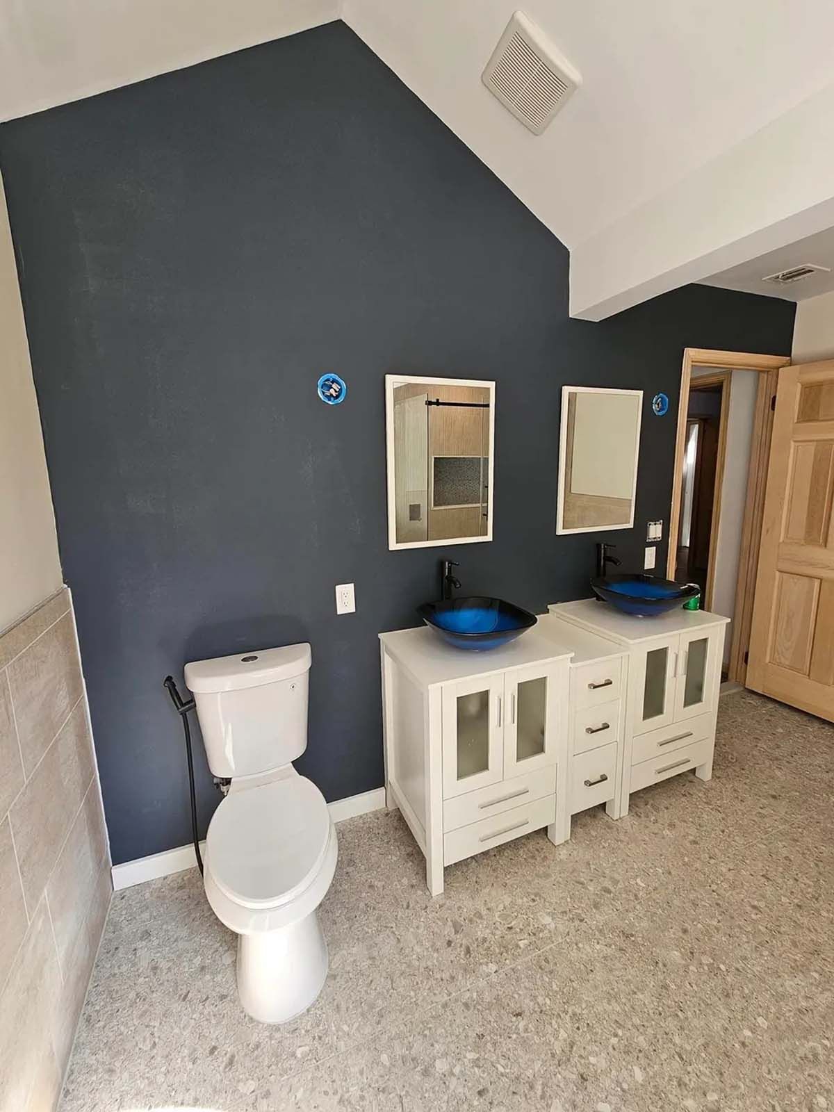 A bathroom with a toilet , sink and mirrors.