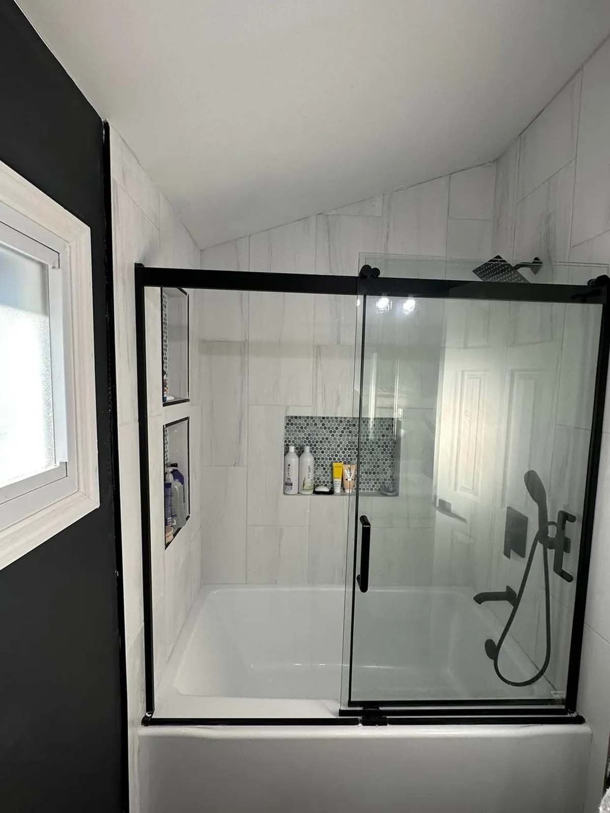 A bathroom with a sliding glass shower door and a bathtub.