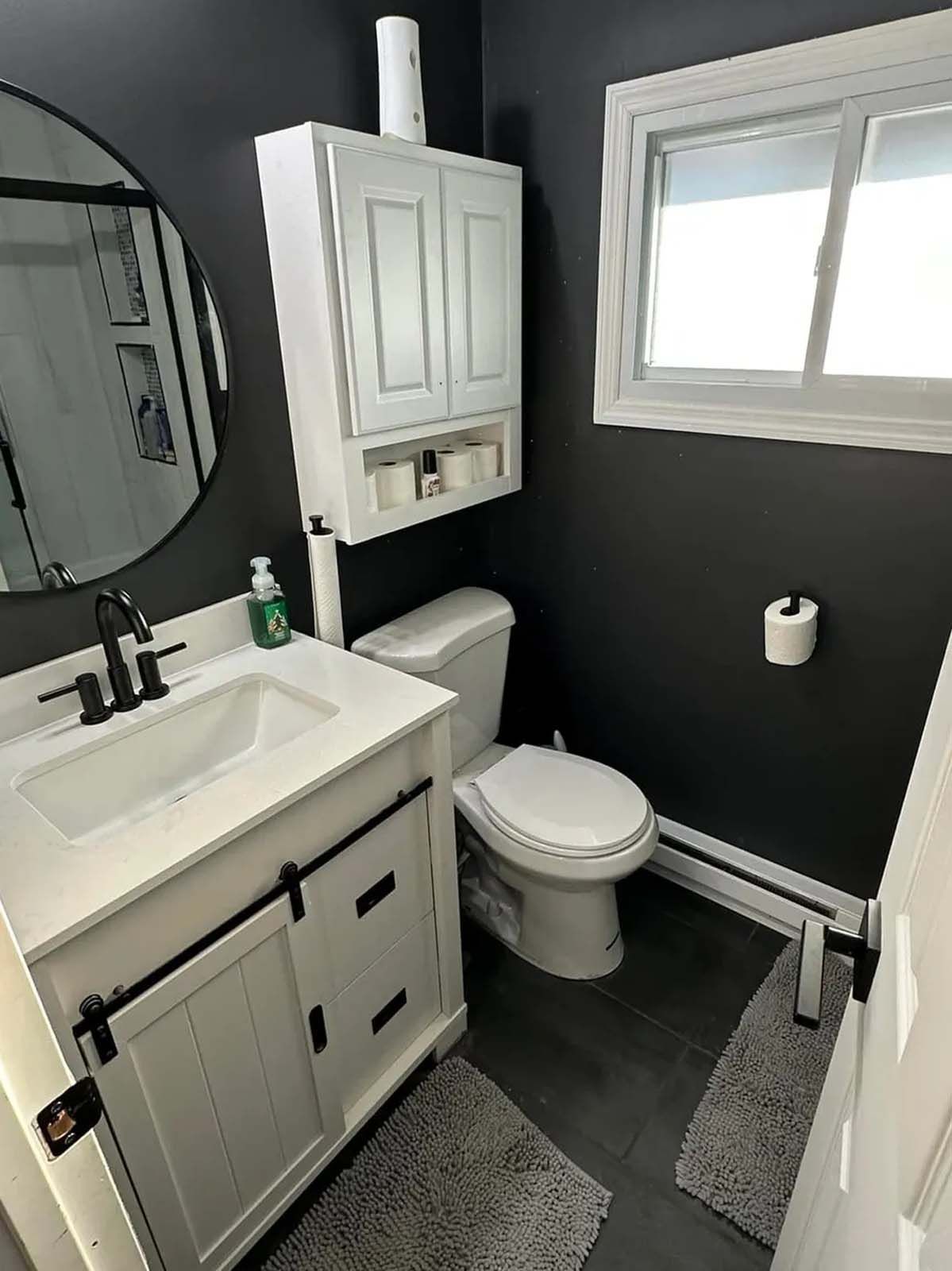 A bathroom with a sink , toilet , mirror and window.