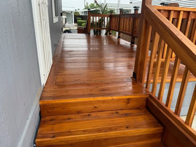 Wooden deck with steps and railing, freshly stained a warm reddish-brown.