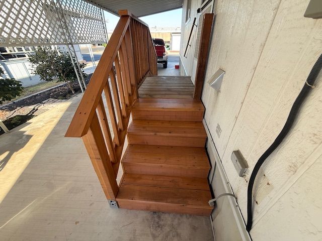 Wooden stairs with railing leading up to a mobile home entrance.