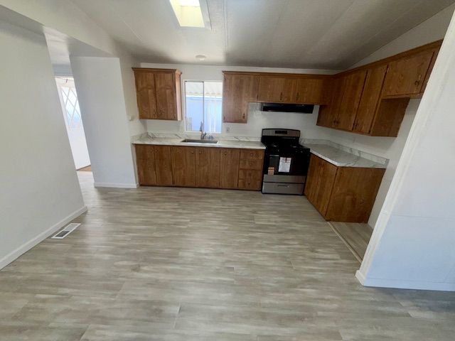 Kitchen with wood cabinets, stainless steel appliances, and gray flooring.