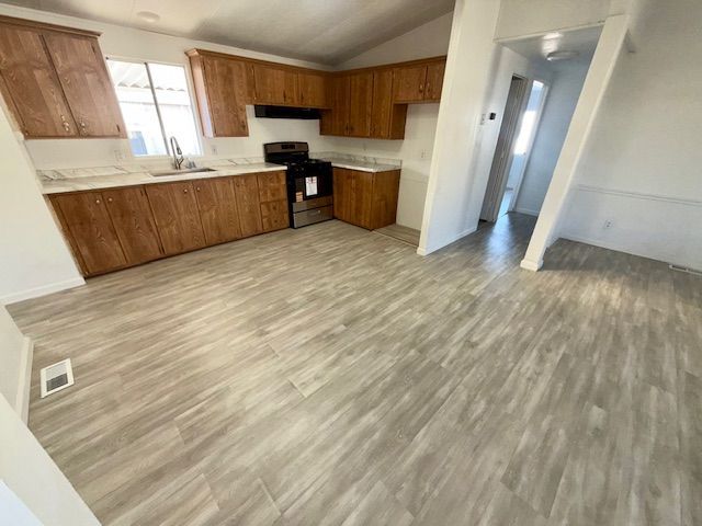 Kitchen with light wood cabinets, gray flooring, and a view of a hallway.